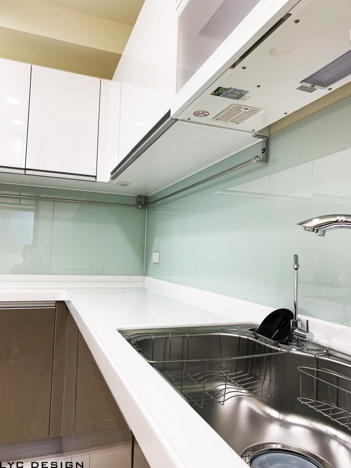 這張照片是一個現代化廚房,最重要的是一個不锈钢水槽,它看起來很乾淨,並且配備了洗碗籃。水槽是白色的台面的一部分,非常适合洗碗和準備食物。