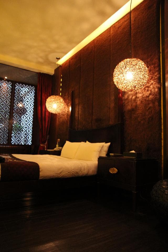 這張照片是一間精緻的臥室,房間採用暖色調的燈光,搭配木質的傢俱,營造出舒適溫馨的氛圍。最顯眼的特徵是床頭上方懸掛著的兩盞圓形燈飾,為臥室增添浪漫優雅的氣息。