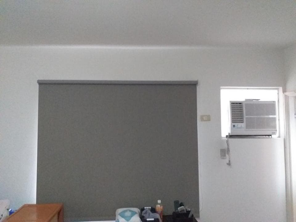 1) 照片顯示一個房間裡的一個灰色的窗簾,在窗簾旁邊是一個白色的冷氣機