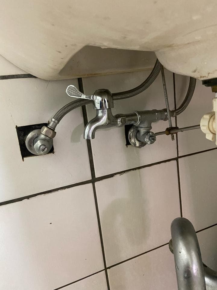 這張照片是一台水龍頭,它安裝在白色的磁磚牆壁上,水龍頭是銀色的,上面有一個旋轉開關。