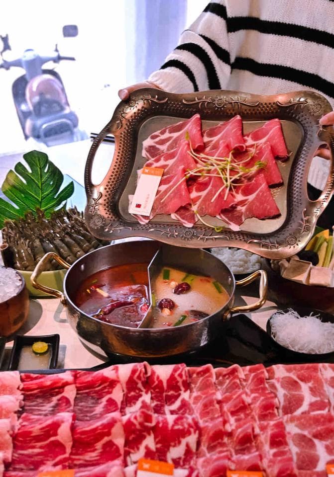 這張「火鍋」的照片是,鍋裡有兩種湯底,旁邊擺著許多肉片,還有盤子裝著肉片,看起來十分美味。